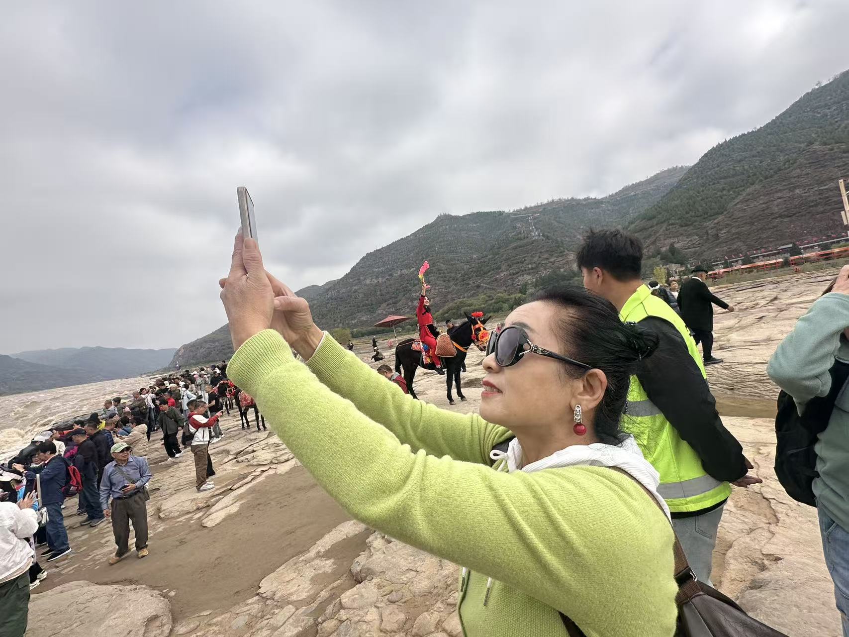 游客在壶口瀑布观景台认真拍照